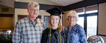 Mom and dad with daughter in graduation cap and gown